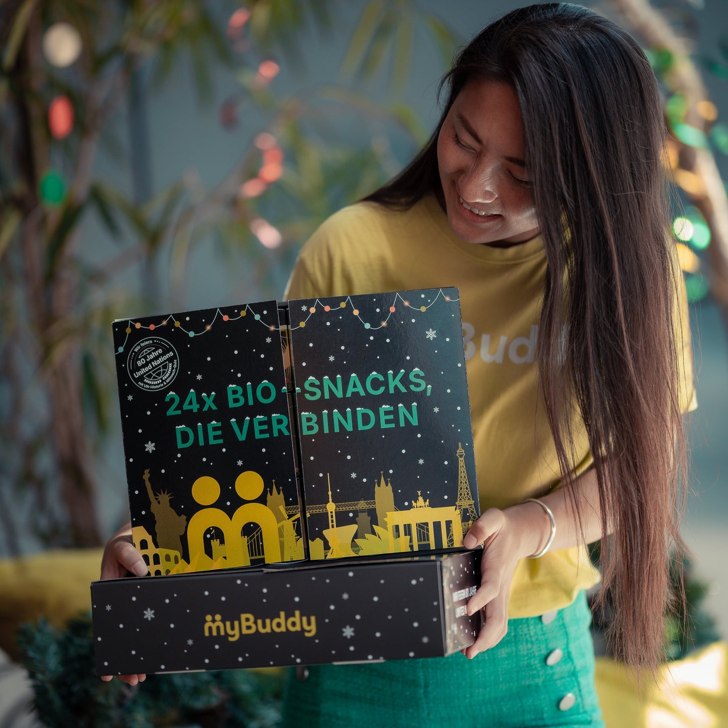 Frau öffnet den myBuddy Adventskalender „24x BIO-Snacks, die verbinden“, davor die myBuddy Versandbox