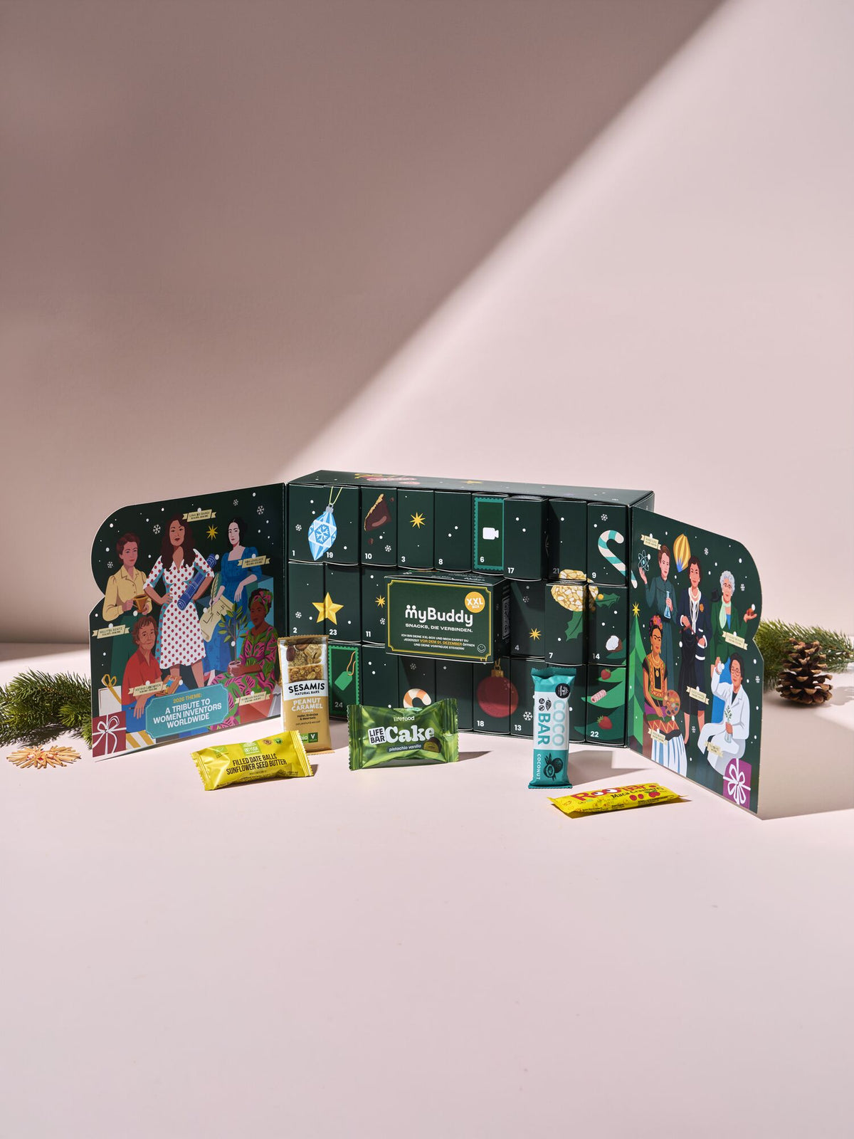 myBuddy Adventskalender 2026, geoeffneter Kalender mit Snacks davor, cremefarbener Hintergrund