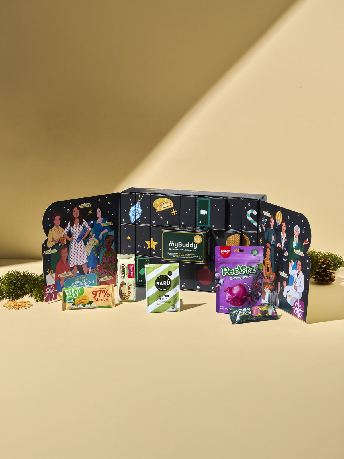 myBuddy Adventskalender 2026, geoeffneter Kalender mit Snacks davor, senfgelber Hintergrund