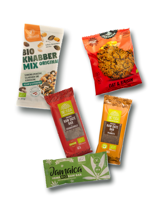 Auswahl einzelner Snacks aus dem myBuddy Adventskalender 2026 BIO-VEGAN, freigestellt: Beutel Bio-Knabbermix, Hafer-Rosinen-Keks, Dattelriegel mit Cranberries, Dattelriegel mit Erdnuss und Hanf-Riegel, jeweils mit Bio- und Vegan-Zeichen auf der Packung, locker überlappend im Flatlay.