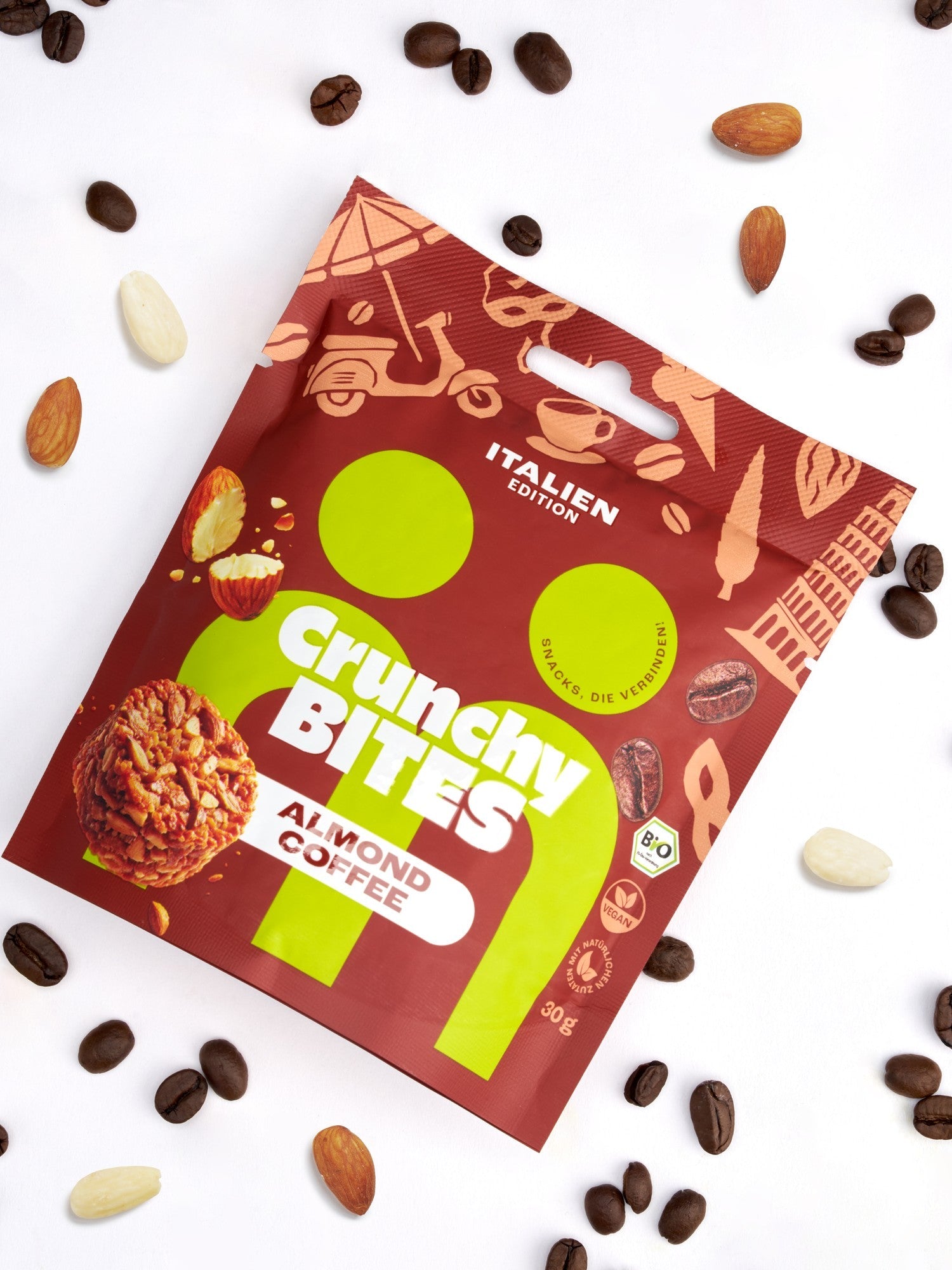 myBuddy Crunchy Nut Bites Almond Coffee aus dem 9er-Set, einzelner 30-g-Beutel im Flatlay mit Kaffeebohnen und Mandeln