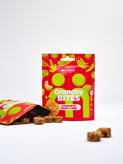 myBuddy Crunchy Nut Bites Cashew Chili Lime aus dem 40er-Set, stehender 30-g-Beutel neben einem geöffneten Beutel mit ausgekippten Bites